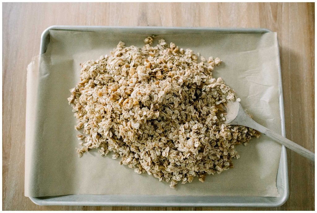 Spreading homemade granola on a sheet pan