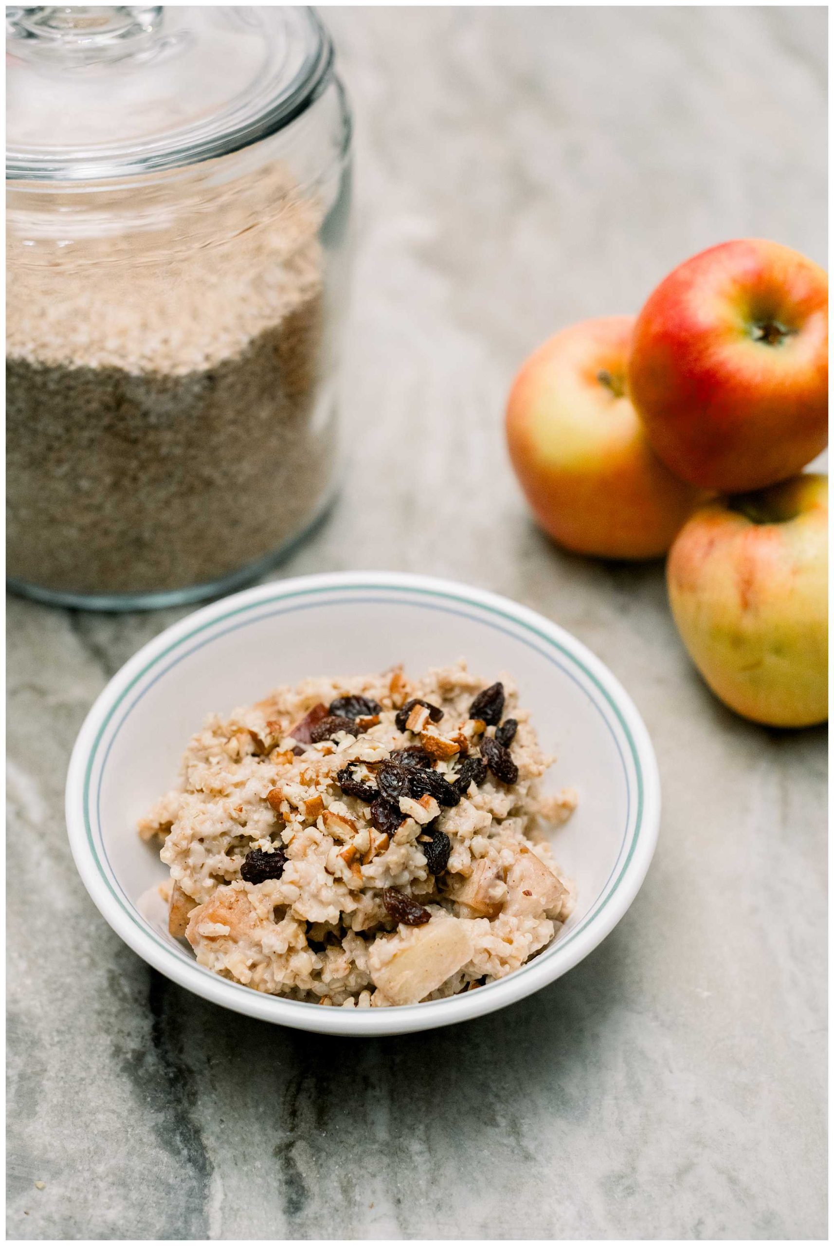 A bowl of Overnight Steel Cut Oats with apples in the background